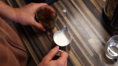 Barmen süt sürahisini köpüklü süt ve bir bardak kahveyle masaya vurur. Yüksek kalite 4k görüntü