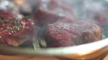 Birisi çatalla tavada kırmızı et pişiriyor. Yemek domuz eti veya sığır etinden oluşabilir ve hayvan ürünleri kullanılarak yapılan tarifin bir parçası olarak hazırlanmaktadır.