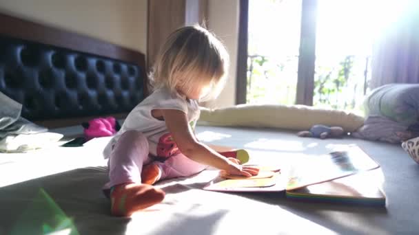 Küçük Kız Yatağın Üzerinde Oturan Bir Kitapta Bir Bulmacayı Katlıyor — Stok video