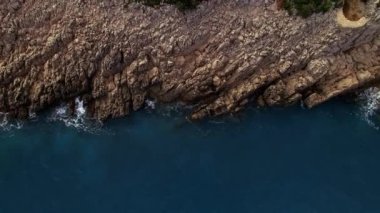 Derin, açık mavi bir denizin üzerindeki kayalık bir uçurumun kenarları. Drone. Yüksek kalite 4k görüntü