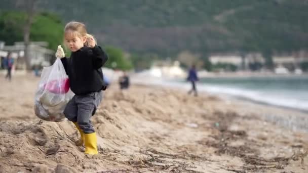 Una Giovane Ragazza Raccoglie Felicemente Spazzatura Lungo Spiaggia Sabbia Godendo — Video Stock