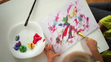 Bir çocuk bir kağıt parçasına yaratıcı sanat tarifi çizmek için fırça kullanıyor. Tablo, yemek malzemeleri ve kirpiklerin eşsiz yazı tipi resimlerini içerir.
