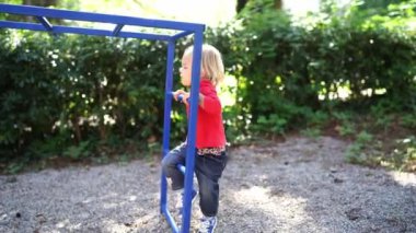 Çocuk parkında çitlere tırmanmaya çalışan küçük bir kız. Yüksek kalite 4k görüntü