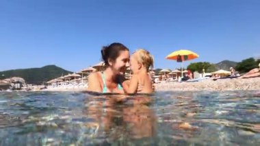 Annem ve küçük bir kız sahildeki sığ sularda bocalayıp duruyorlar. Yüksek kalite 4k görüntü