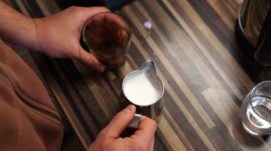 Barmen süt sürahisini köpüklü süt ve bir bardak kahveyle masaya vurur. Yüksek kalite 4k görüntü