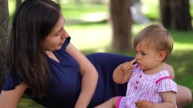 Annem çimlerin üzerinde yatarken burnunu parmağıyla dürten küçük bir kızla konuşuyor. Yüksek kalite 4k görüntü