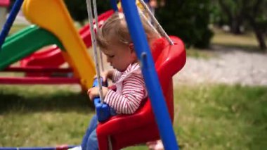 Küçük kız salıncakta sallanıyor oyun parkındaki direğe tutunuyor. Yüksek kalite 4k görüntü