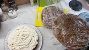 Kesme tahtasıyla birlikte iki tabak yemek bir masanın üzerine konur. Tabaklarda kürk, karasal hayvan eti ve evcil hayvan malzemeleri gibi eşsiz bir mutfak malzemesi var.