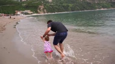 Babam kumsalda koşup küçük bir kızın elini tutuyor. Yüksek kalite 4k görüntü