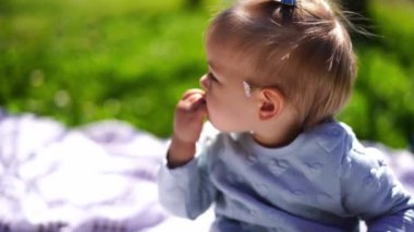 Kulağının arkasında papatya olan küçük bir kız elini ısırıp başını yana çeviriyor. Yüksek kalite 4k görüntü