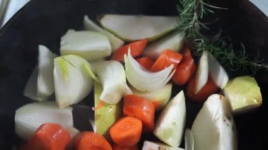 Şef baharatla pişirilmiş doğranmış sebzelere yarım baş sarımsak ekliyor. Yüksek kalite 4k görüntü
