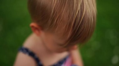 Küçük kız yeşil çimlerin üzerinde duran bir şişeden limonla su içiyor. Yüksek kalite 4k görüntü