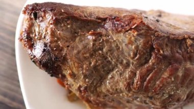 Bifteğin üstünde, tabakta kahverengi bir kabukla birlikte buhar yükselir. Yüksek kalite 4k görüntü