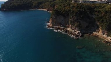 Yeşillik, yemyeşil sulara bakan, doğal kıyı ve okyanus manzaralarını gösteren, nefes kesici bir uçurum manzarası.