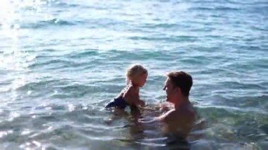 Babam kucağında küçük bir kızla suyun derinliklerine iniyor. Yüksek kalite 4k görüntü