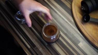 Barista bir kaşıkla kavanozdan öğütülmüş kahveyi alır ve kahve makinesinden külahın içine döker. Yüksek kalite 4k görüntü
