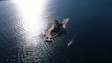 Uçsuz bucaksız bir sıvı bedenin huzurlu yüzeyinde süzülen bir teknenin hava görüntüsü çarpıcı bir manzara sergiliyor ve resim gibi bir olay yaratıyor.