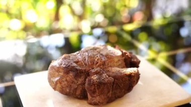 Kızarmış biftek, balkondaki bir masanın tahta kesme tahtasının üzerinde duruyor. Yüksek kaliteli FullHD görüntüler