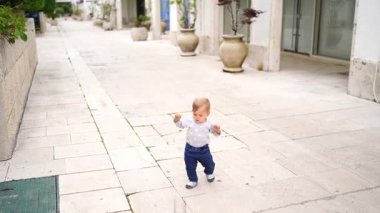 Küçük bebek bahçede kollarını dengelemek için fayansların üzerinde yürüyor. Yüksek kalite 4k görüntü