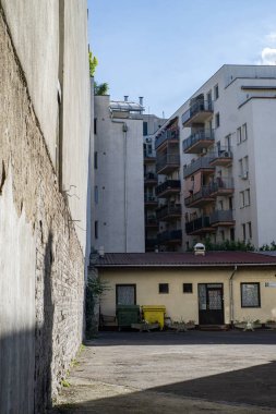 residential buildings and a small house with a parking lot in front of it in the sunshine
