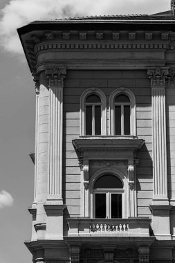 a residential building with windows of old construction on a sunny day with a few clouds and some shade