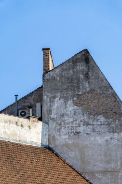 a residential building with chimneys and a brick roof, under a blue sky in budapest