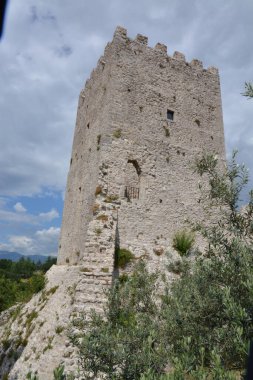 Bir kulesi ve arka planında küçük bir kulesi olan taş bir duvarın güzel bir görüntüsü.