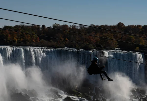 Niagara Şelalesi, Ontario, Kanada 'da sonbaharda halatla kayma macerası yaşayan bir insan. Amerikan Şelaleleri arka planda..