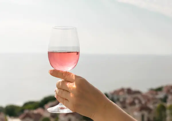 A Glass of Rose Wine in a Woman\'s Hand against the Sky and Sea
