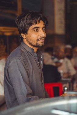Portrait of a poor middle aged Pakistani man, Pathan, working in his shop clipart