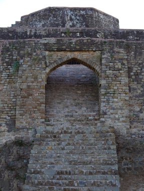 Eski çağlardan kalma eski bir ortaçağ kavisli kale kapısına giden taş merdivenler. Mimari taş kemer yolu ve etrafını saran taş duvar var.
