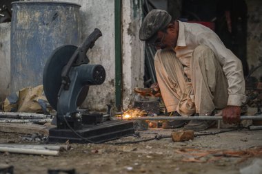 Zavallı Pakistanlı kaynakçı boruları ve sokak atölyesindeki metal çubuklar.