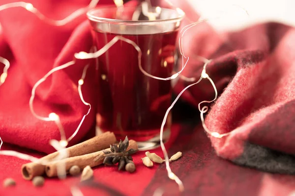 a glass cup of a red warming drink (tea, mulled wine, punch). ingredients for winter hot drinks. beautiful winter background.