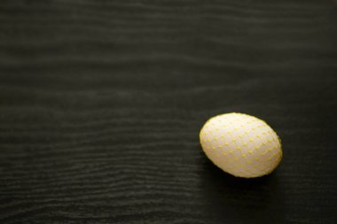 Dekoratif sarı ızgaralı tavuk yumurtası ve koyu bir arka plan. Paskalya.