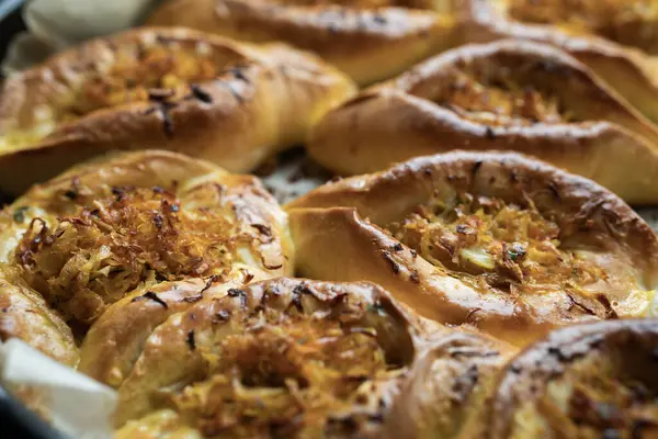 Annem evde yemek pişiriyor. Lahanalı çörekler fırın tepsisinde.