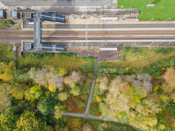 Aerial view of rural railway station and train tracks. Kirkstall Forge Train Station, Leeds, West Yorkshire, viewed from above with autumn trees.