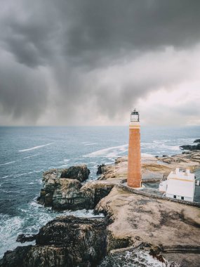 Storm clouds over Butt of Lewis Lighthouse on the Isle of Lewis in the Outer Hebrides of Scotland. Vertical drone shot.