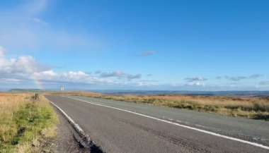 Güneşli bir günde A640 New Hey Road, Kirklees 'de araba sürüşü zamanı. Slaithewaite Moor manzaralı M62 'ye giden popüler manzaralı alternatif rota.