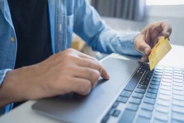 Bilgisayarı kullanırken kredi kartı tutan, internetten alışveriş yapan, internetten alışveriş yapan bir adam. E-ticaret e-bankacılık servisi. Bilgisayarda çalışan başarılı bir serbest yazar. Çevrimiçi güvenli ödeme.
