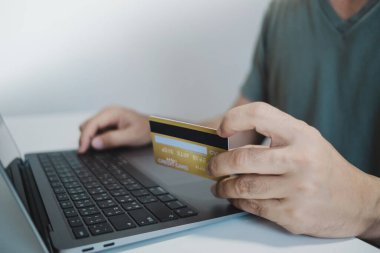 Bilgisayarı kullanırken kredi kartı tutan, internetten alışveriş yapan, internetten alışveriş yapan bir adam. E-ticaret e-bankacılık servisi. Bilgisayarda çalışan başarılı bir serbest yazar. Çevrimiçi güvenli ödeme.