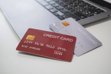 Kredi kartları ve dizüstü bilgisayarı beyaz masaya koyun. Nakitsiz teknoloji ve kredi kartı ödeme konsepti, işlemin kolaylığı için internet üzerinden.