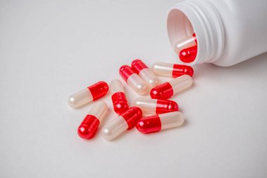 Kırmızı ve beyaz ilaç kapsüllü şişe kaplarını beyaz arka planda fotokopi alanı ile kapatın. Güzellik, sağlık, sağlık ve tıp konsepti