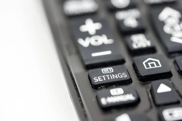 Close-up of a TV remote control isolated on white background with focus on the settings button, concept of smart TV