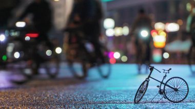 Bir sürü insan bisikletçi, gece bisikleti sürücüsü, küçük ölçekli bisiklet modelinin arka planına karşı aydınlanmış şehir caddesi. Spor yaşam tarzı kavramı