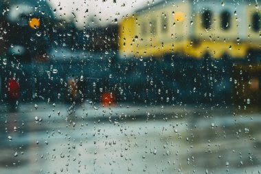 Camlara yağmur damlaları, gece aydınlatması, pencereden manzara. Bulanık soyut arkaplan