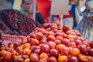 Markette sergilenen büyük olgun şeftali yığını, doğal canlı bir görüntü.