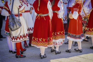 Renkli desenli ve nakışlı parlak geleneksel Bulgar halk kostümleri giymiş tanınmamış bir grup kadın.