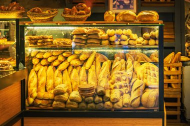 Fırın vitrininde çeşitli taze ekmekler, baget, rulo ve altın kabuklu somunlar da var.