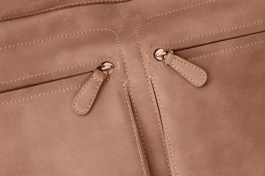 Fermuarlı cepleri olan deri ten rengi bir çanta.