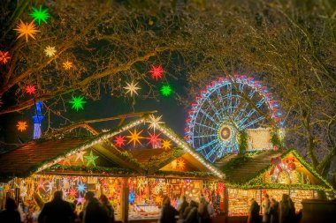 Christmas market at night with bright lights, colorful star decorations and a Ferris wheel clipart